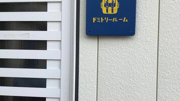 A dormitory room sign with a bed and a window.