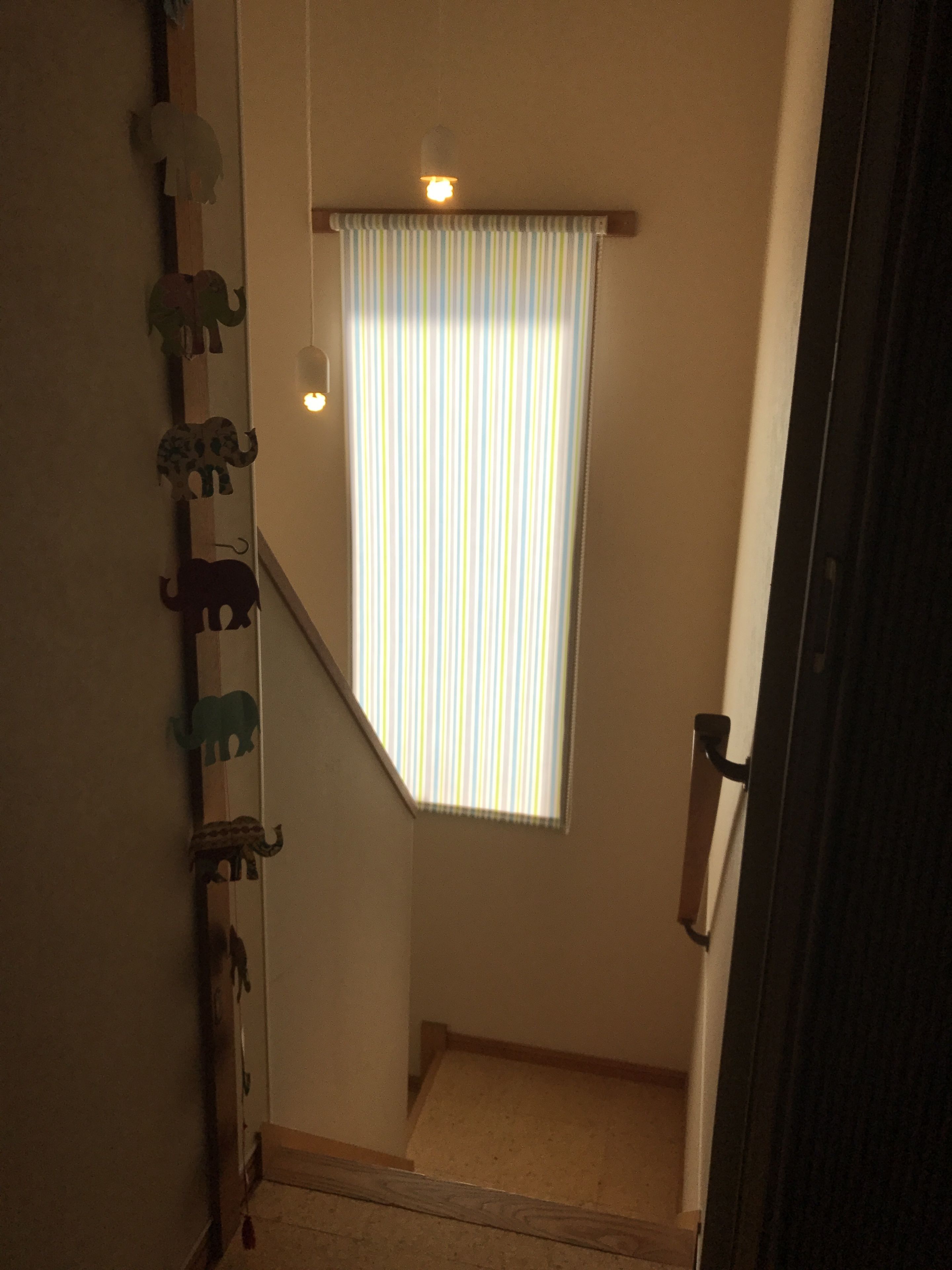 A narrow stairway with a striped window and a wall-mounted elephant decoration.