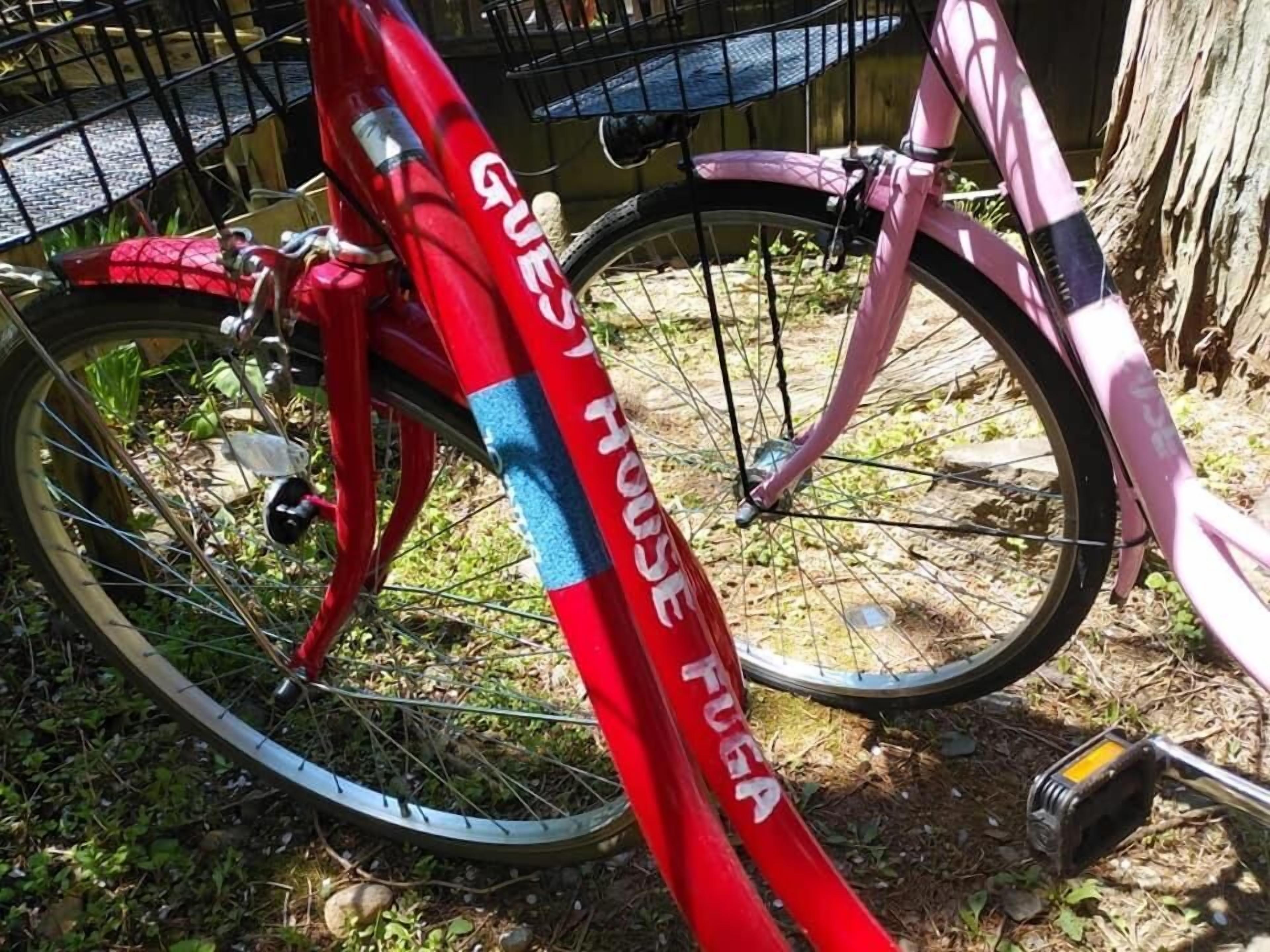 A red bicycle with "GUEST HOUSE" written on the frame, parked outdoors.