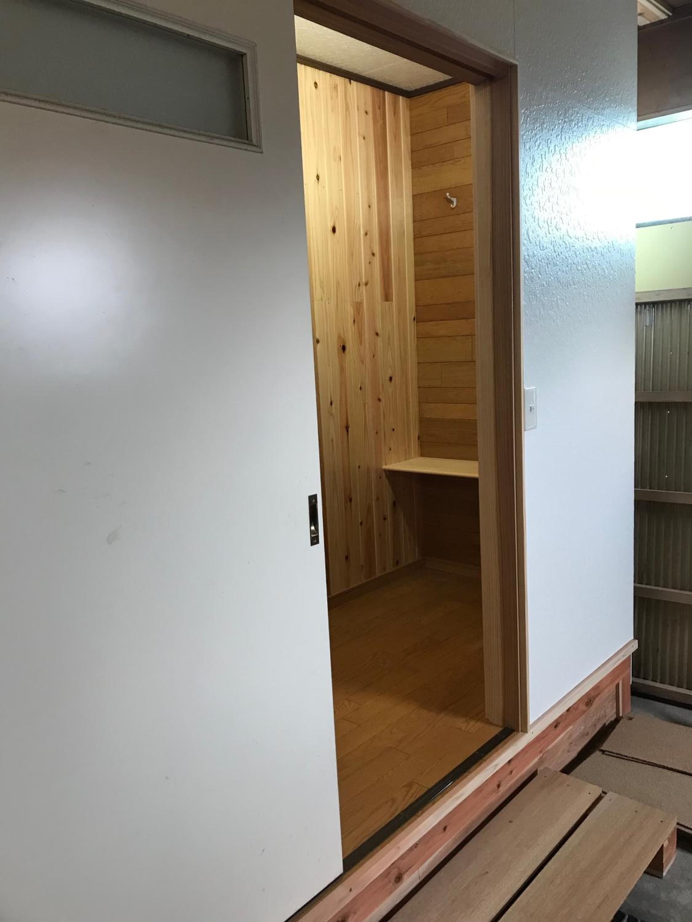 A room with a wooden door leading to a space with wooden paneling.