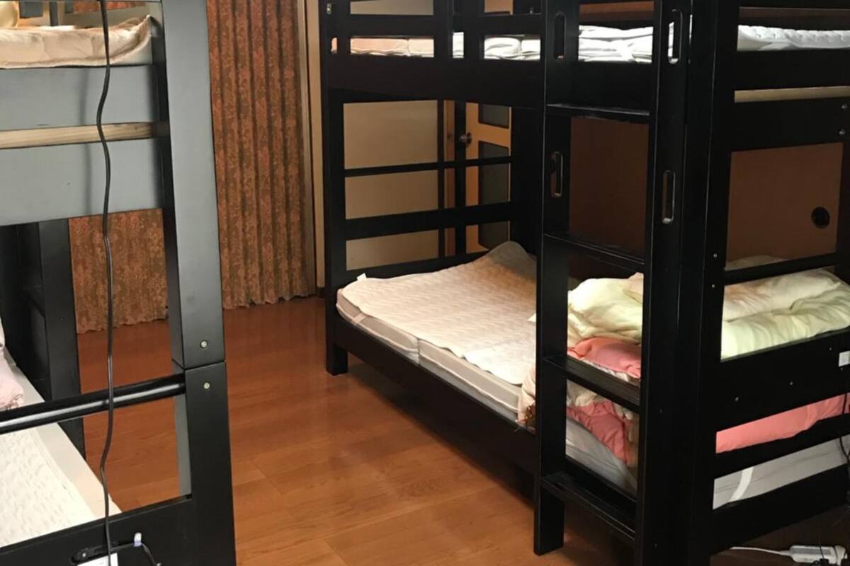 A bunk bed room with wooden flooring and a ceiling light fixture.