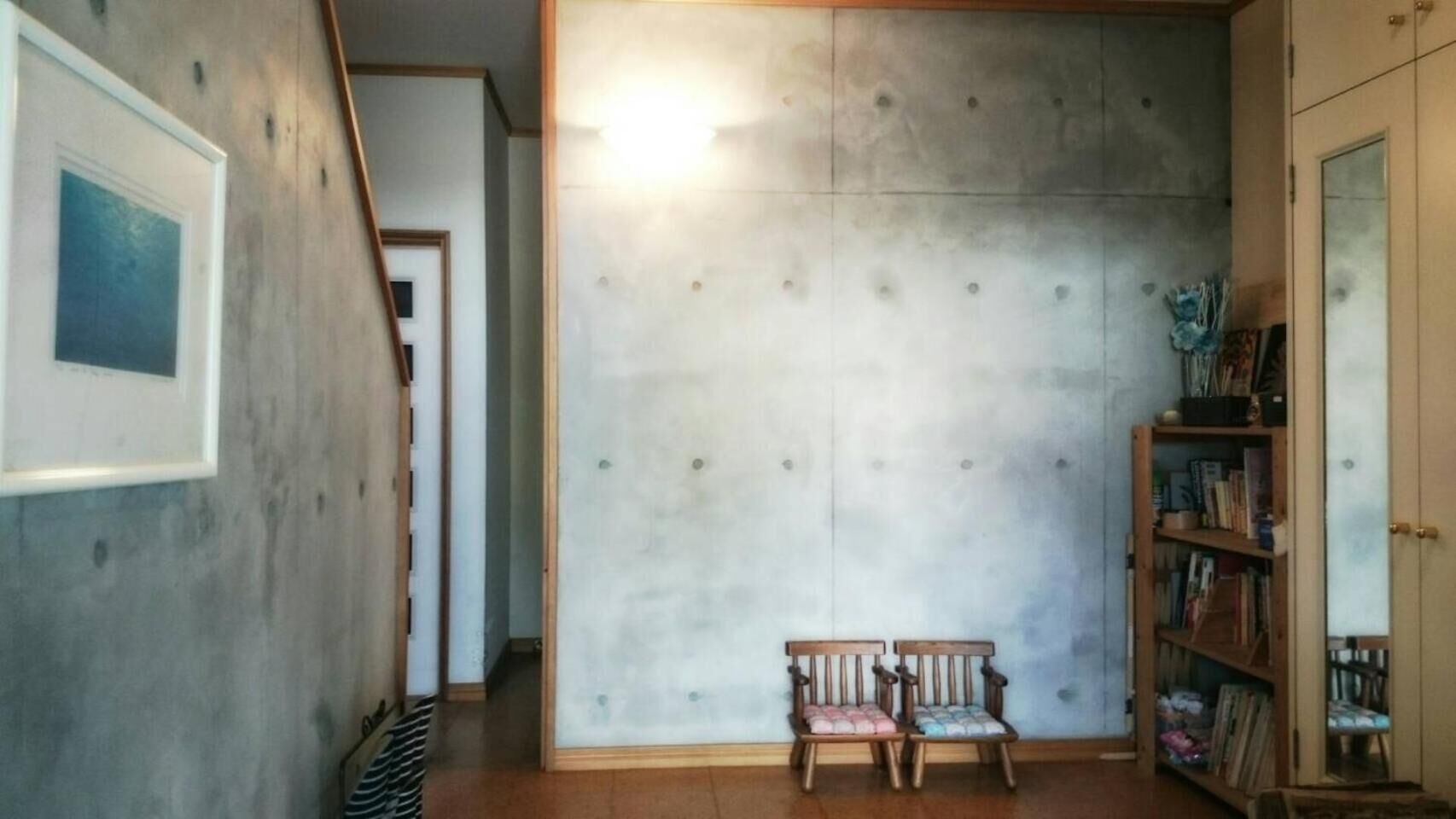 Un pasillo con un banco de madera, una estantería y un cuadro en la pared.