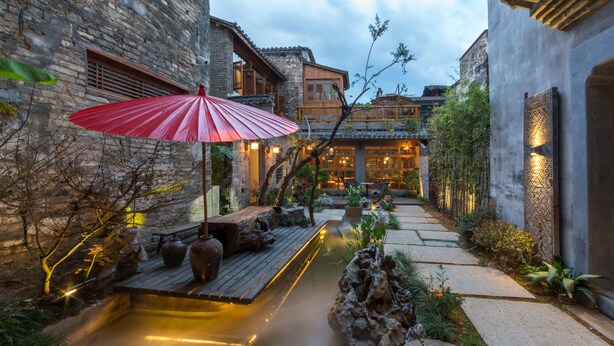 A serene courtyard with a wooden deck, a red umbrella, and a water feature. - Huangshan Huanchun·Bingyu Resort (Huangshan)