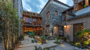 A traditional courtyard with stone pathways, a small water feature, and bamboo plants. - Huangshan Huanchun·Bingyu Resort (Huangshan)