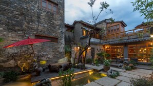 A traditional courtyard with stone walls, a wooden deck, and a small water feature. - Huangshan Huanchun·Bingyu Resort (Huangshan)