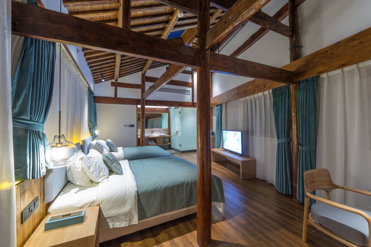 Une chambre à coucher avec un plafond en bois, un lit, une table de chevet, une chaise et un téléviseur.