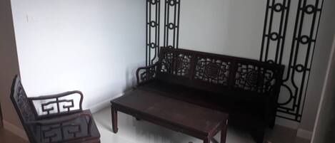A room with a dark wooden sofa and a matching armchair, a small wooden coffee table, and a decorative metal gate.