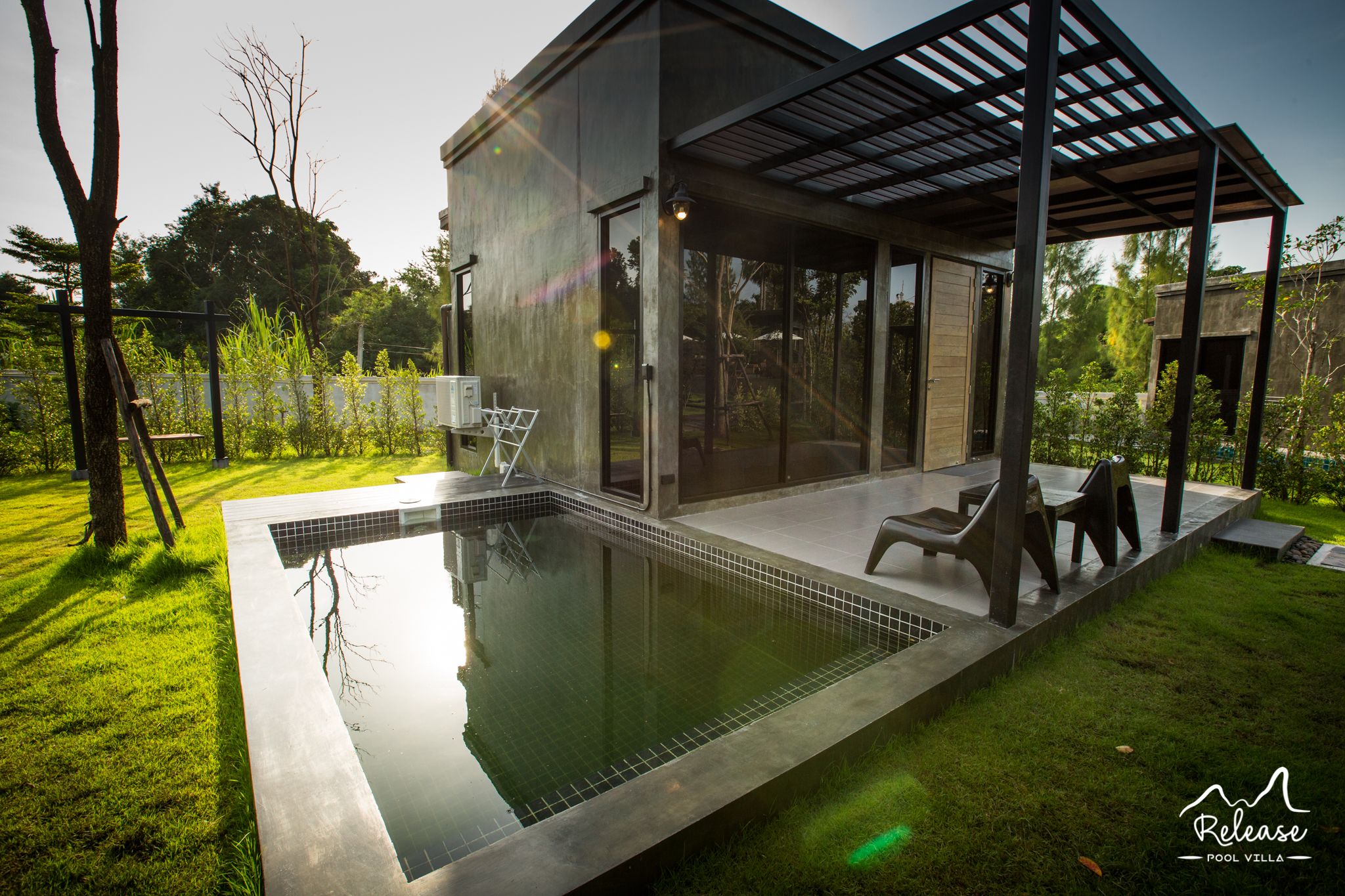 A modern pool villa with a glass-enclosed patio, a swimming pool, and outdoor seating.