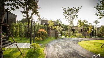 A residential area with a curved driveway, a wooden deck, and a stone pathway.