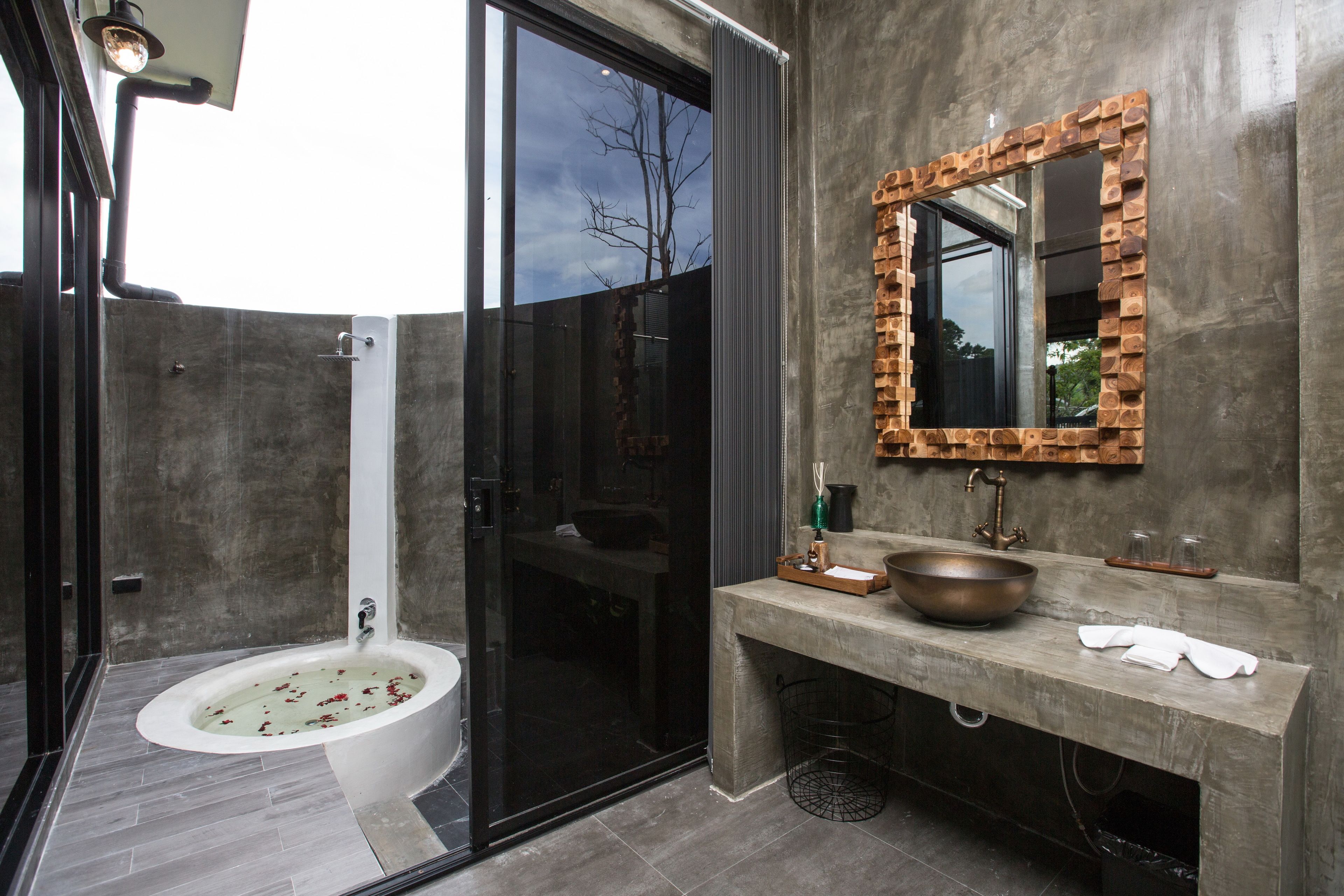 A modern bathroom with a glass-enclosed shower, a freestanding bathtub, and a large mirror with a brick frame.