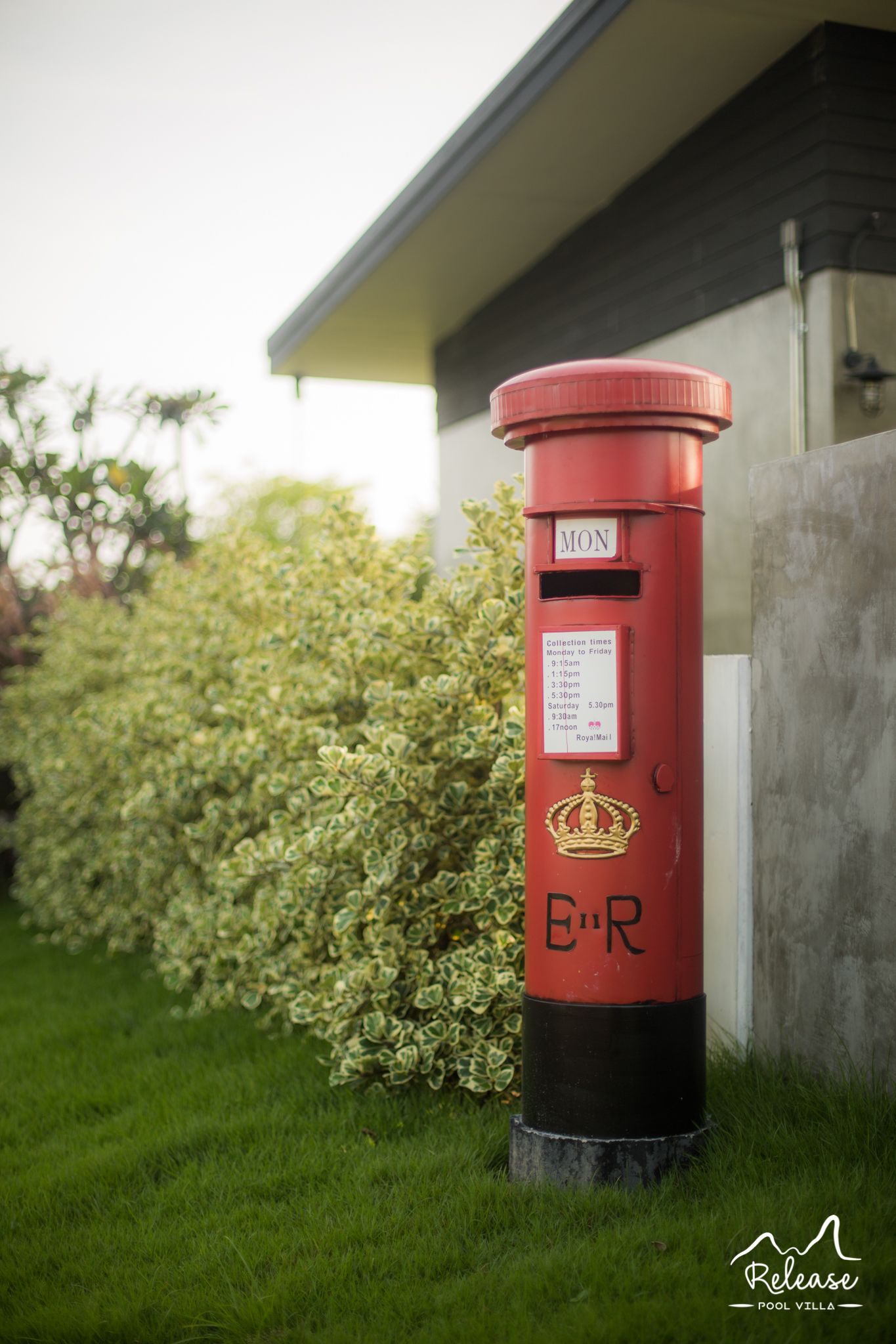 A red British post box with collection times and a crown emblem.