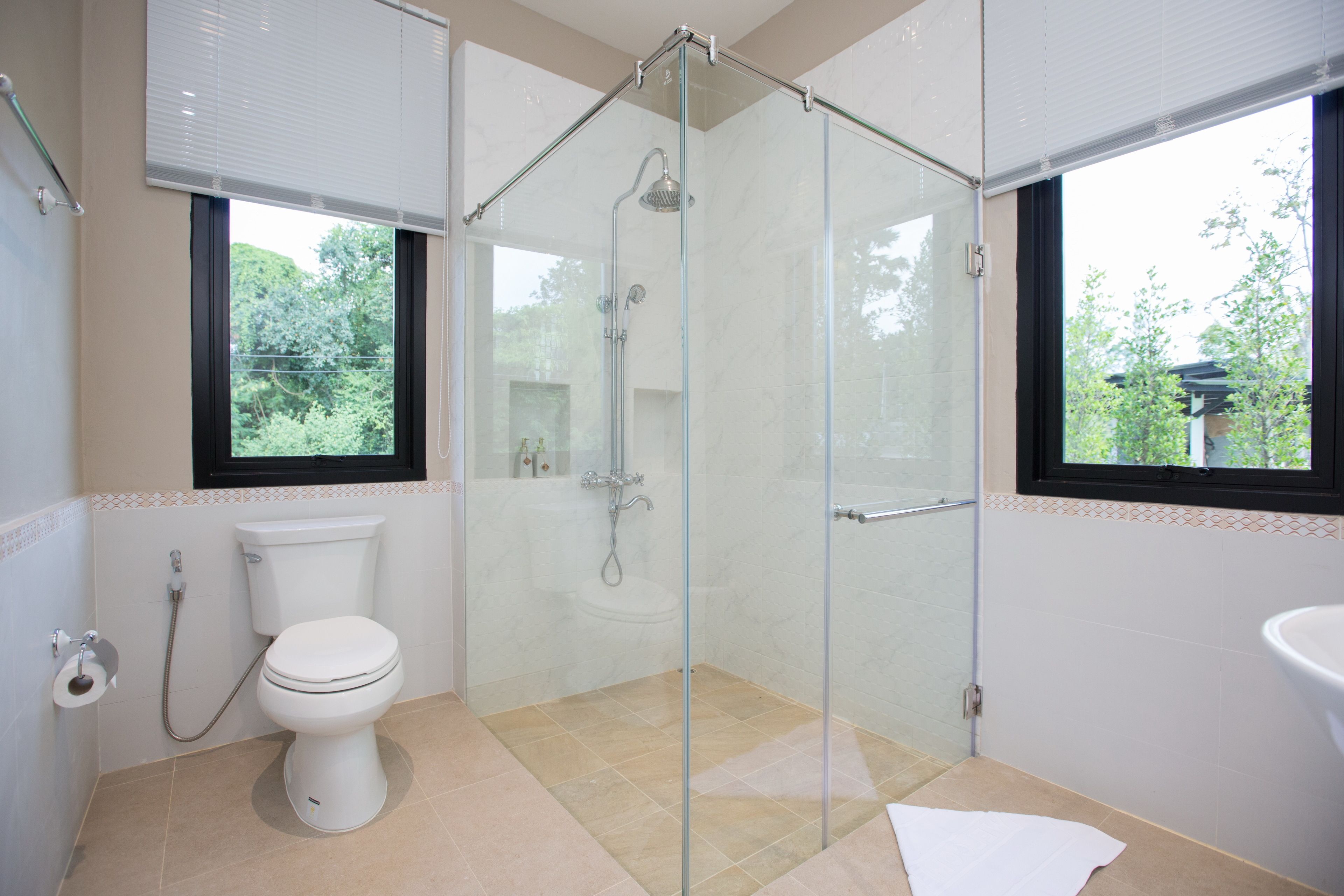 Un baño moderno con ducha de mampara de vidrio, inodoro y lavamanos.