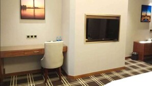 Ett hotellrum med ett skrivbord, en stol och ett stort fönster.