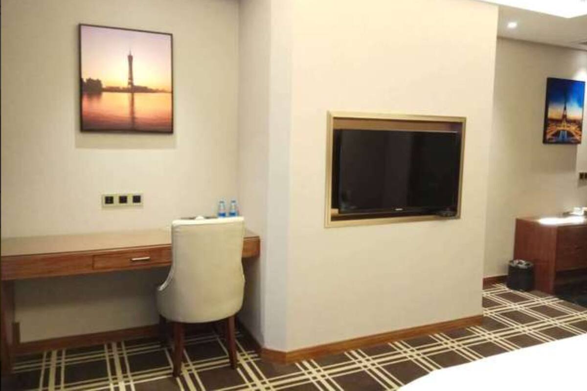 Une chambre d’hôtel équipée d’un bureau, d’une chaise et d’une grande fenêtre.