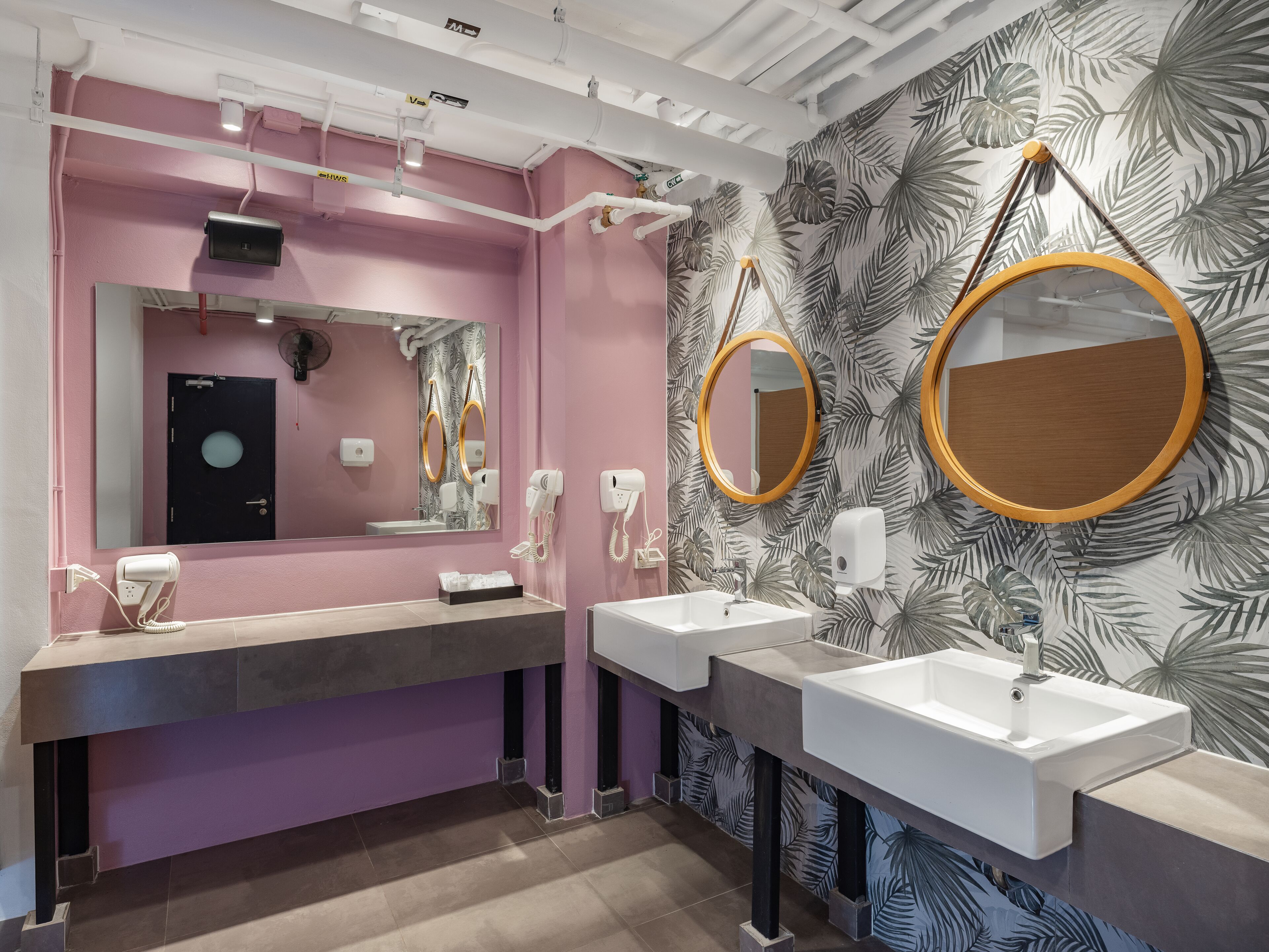 A modern bathroom with two sinks, a large mirror, and a hairdryer.