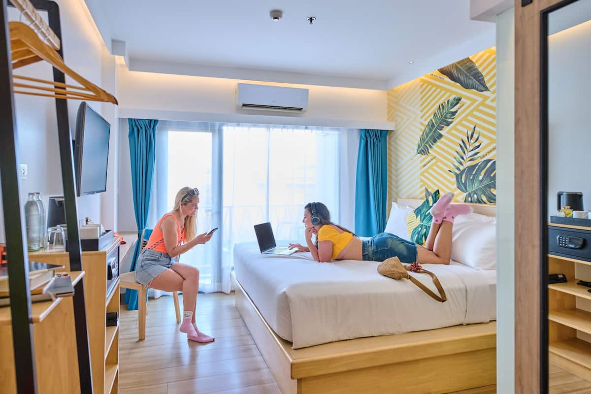 Une chambre d’hôtel équipée d’un lit, d’un bureau, d’une chaise, d’une télévision et d’une fenêtre avec des rideaux.