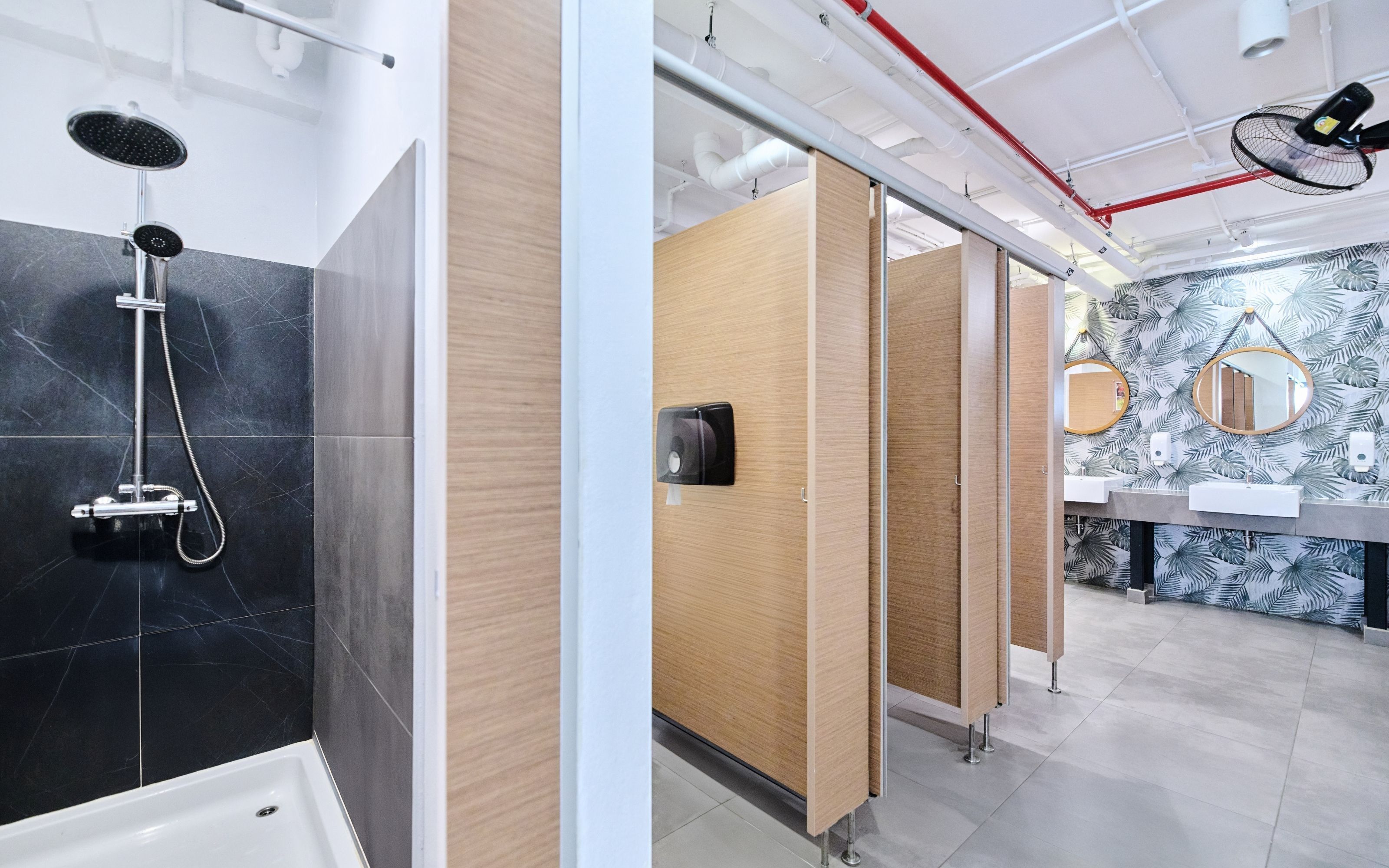 Un baño moderno con ducha, separadores de madera, espejo y pared con diseño.