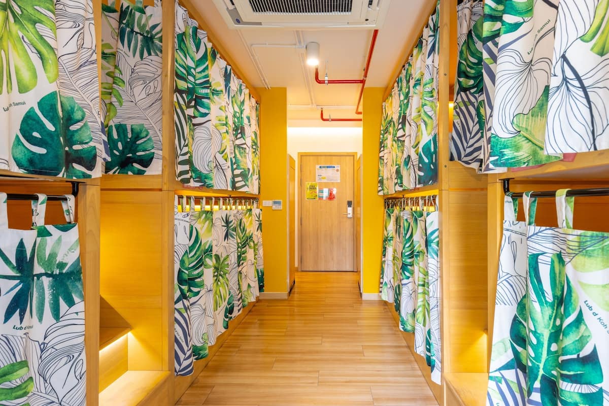 Un couloir doté d’un plancher en bois et de murs décorés de motifs de feuilles tropicales.
