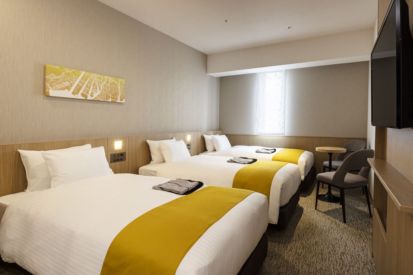 Una habitación de hotel con dos camas, televisión, una mesita y una silla.