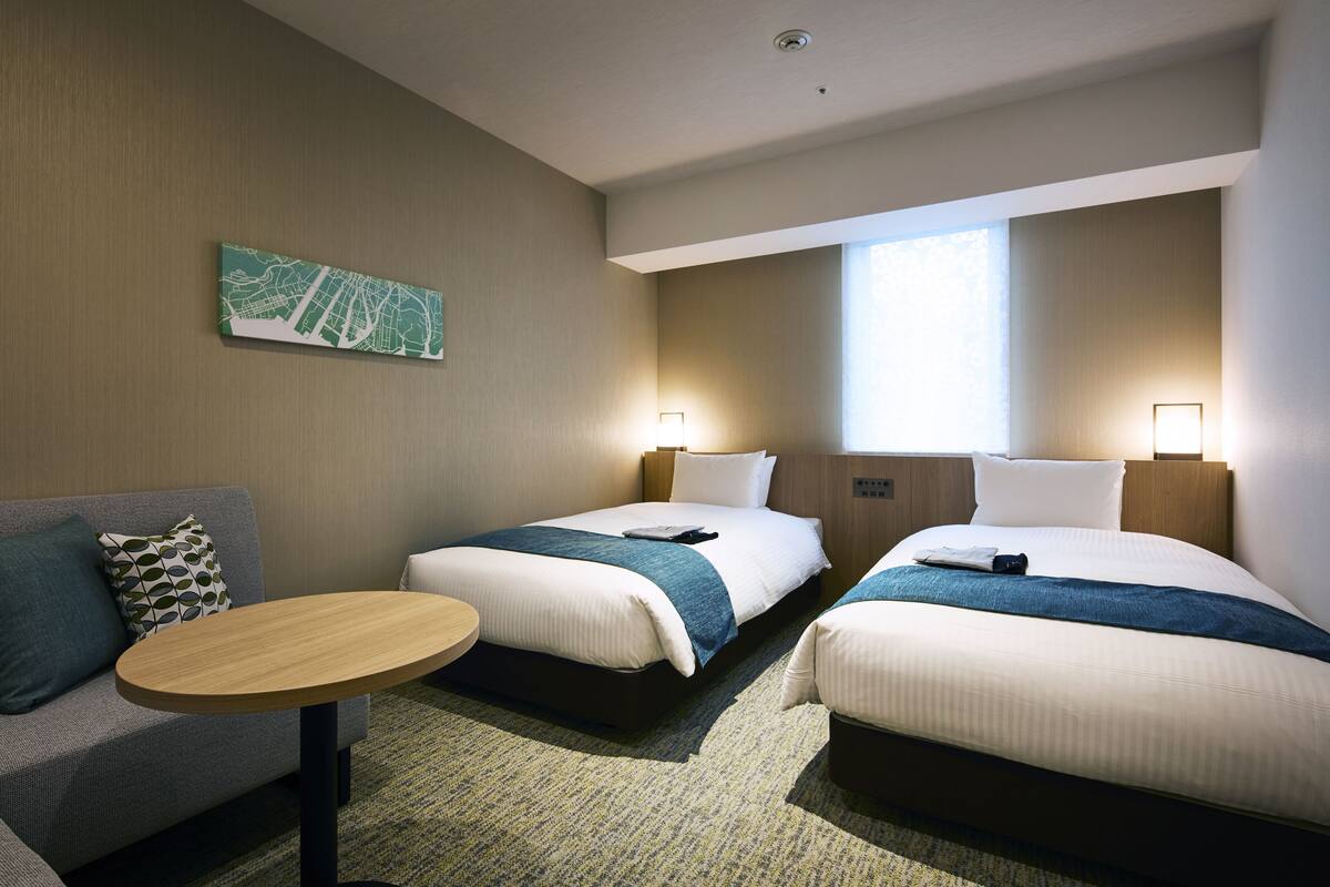 Habitación de hotel con dos camas, un sofá, una mesita y un mapa en la pared.