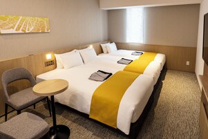 Ein Hotelzimmer mit zwei Betten, einem kleinen runden Tisch, einem Stuhl und einer Karte an der Wand.