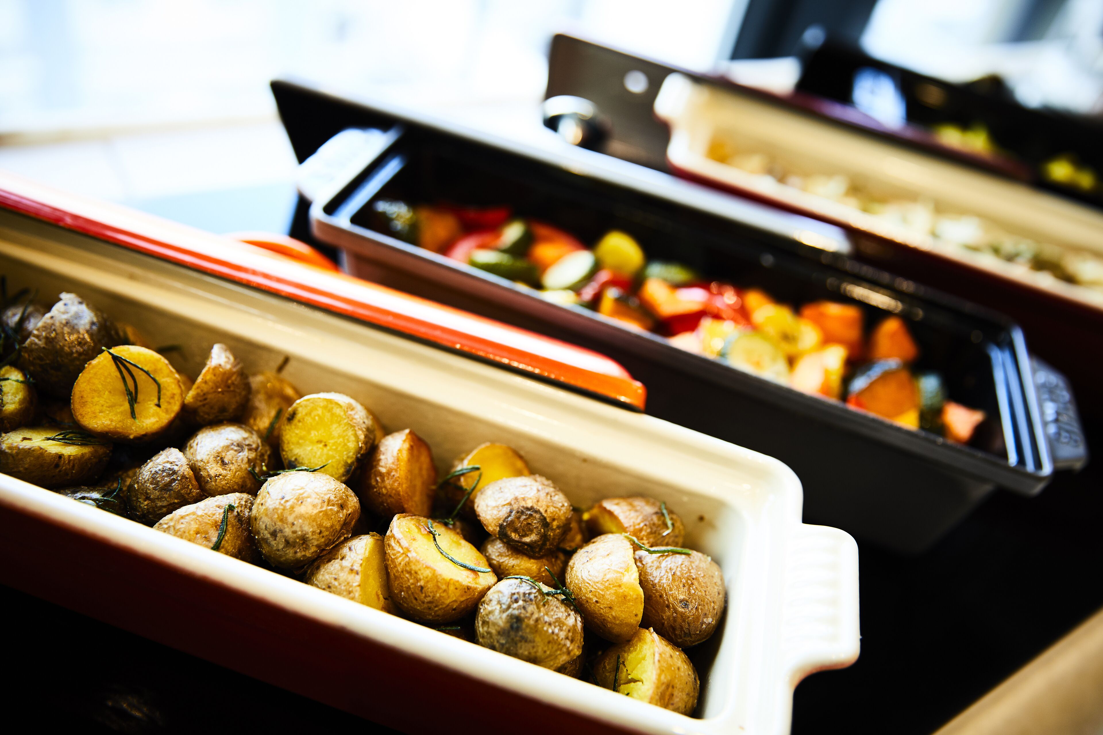 A buffet with various dishes including roasted potatoes and mixed vegetables.