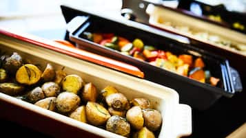 A buffet with various dishes including roasted potatoes and mixed vegetables.