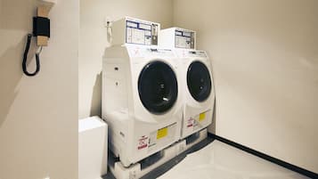A laundry room with two front-loading washing machines and a wall-mounted phone.