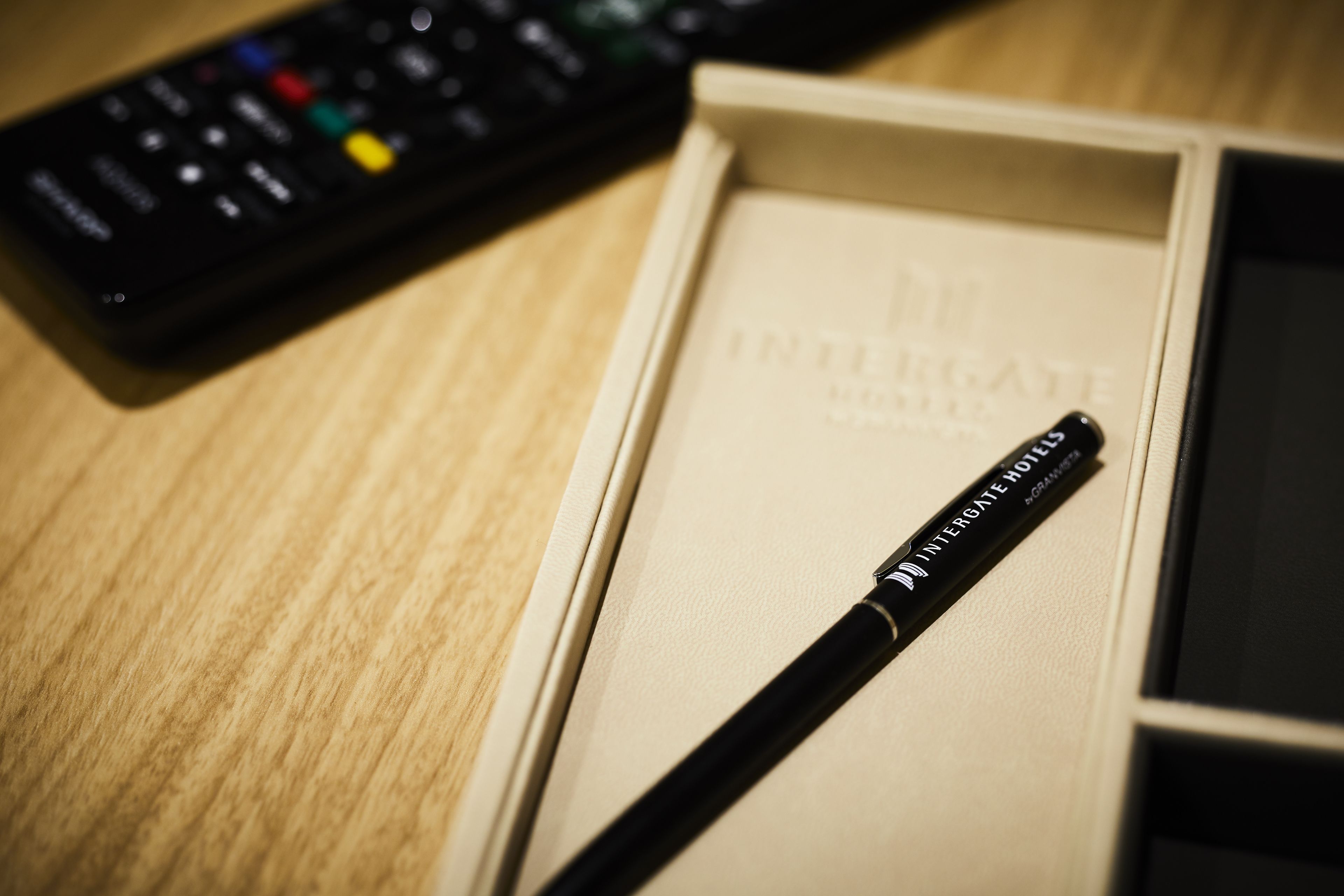 A remote control and a pen in a box labeled "INTERGATE HOTEL."