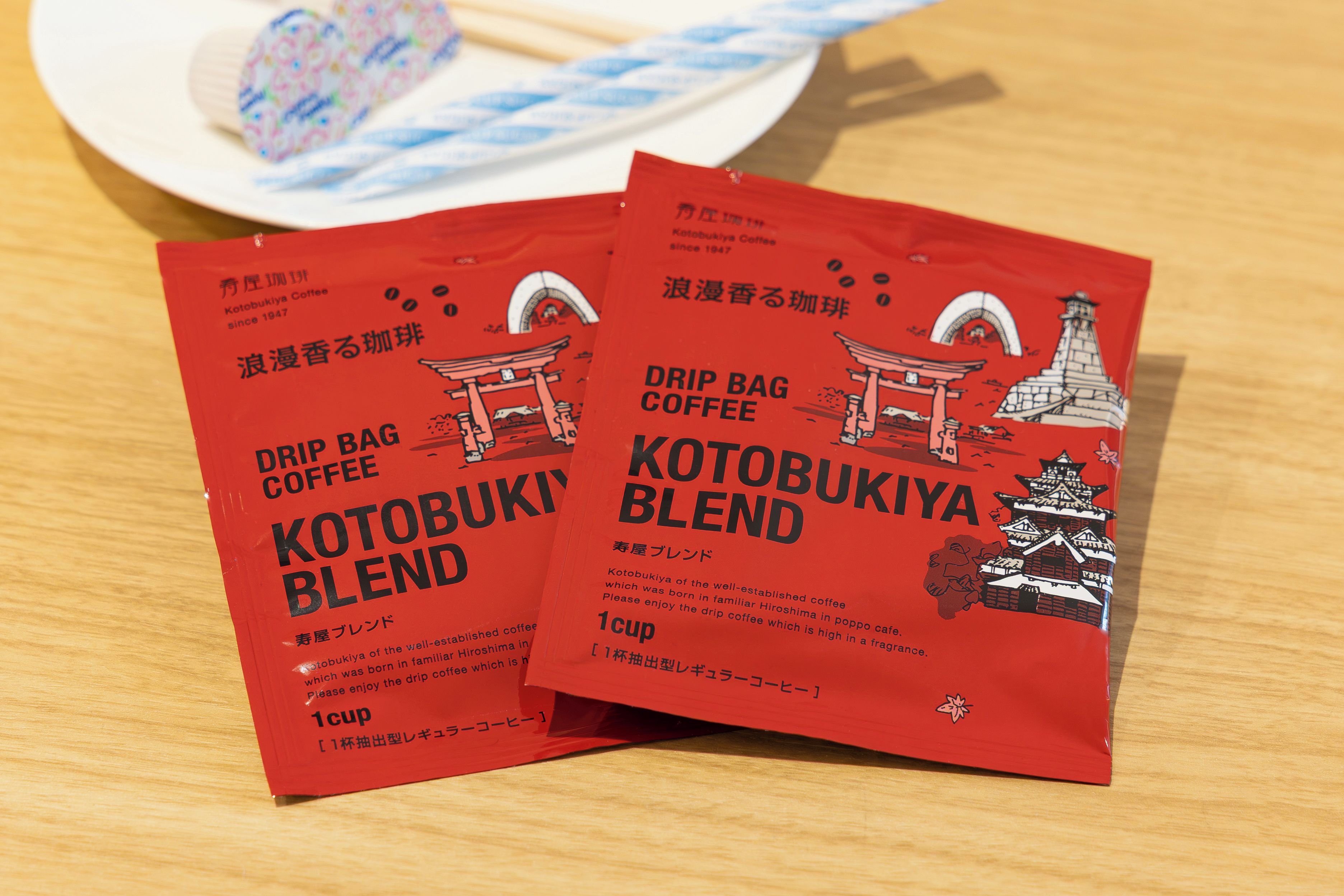 Two red drip coffee bags with Japanese text and illustrations of traditional Japanese architecture.