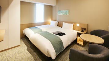 A hotel room with a large bed, a small table, a chair, and a nightstand.