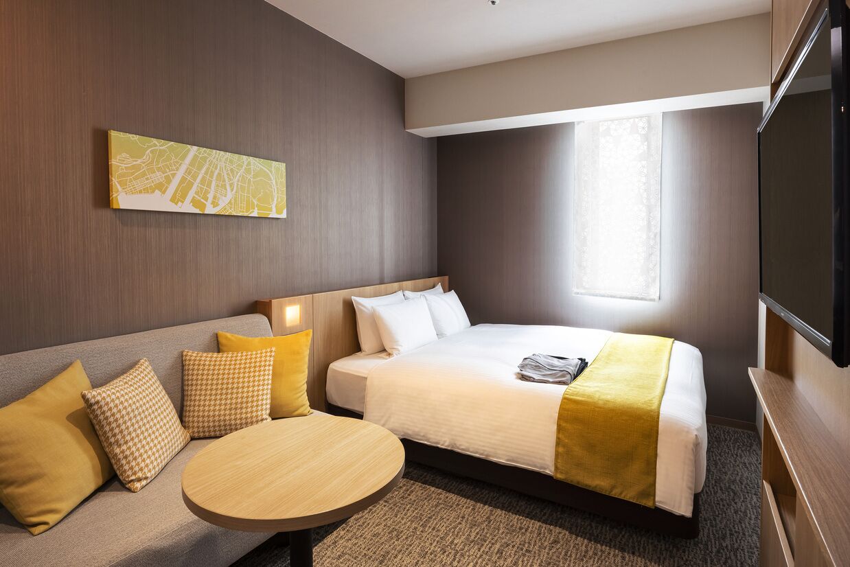 Una habitación de hotel con cama, sofá, mesa redonda y un cuadro con un mapa en la pared.