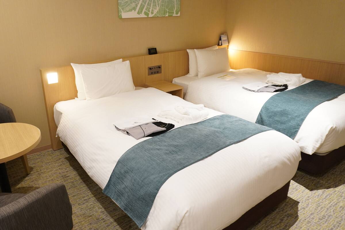 Una habitación de hotel con dos camas, una mesita y una silla.