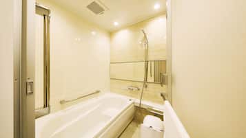 A modern bathroom with a large bathtub, a shower area, and a toilet.