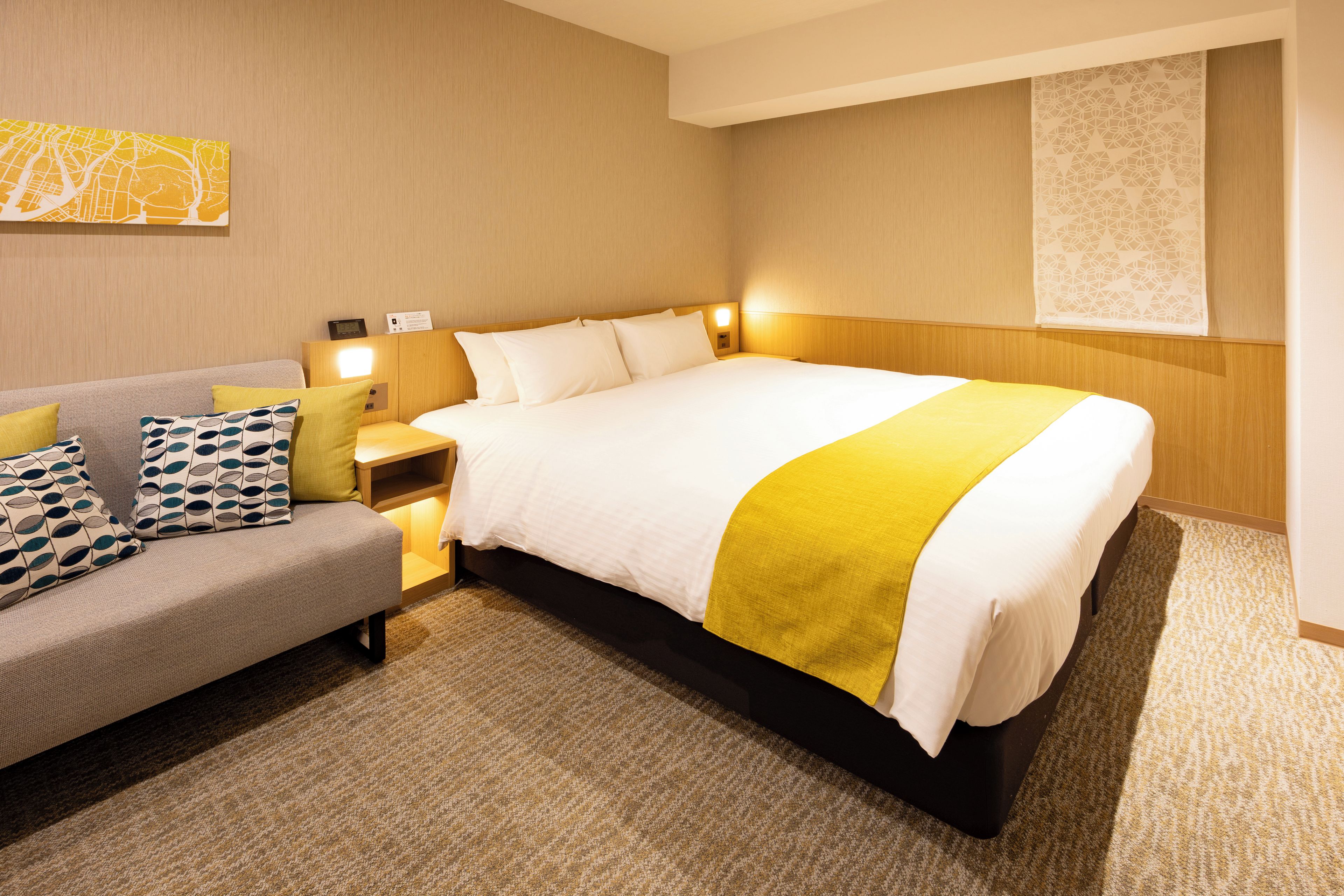 A hotel room with a bed, a sofa, and a nightstand.