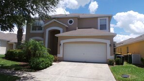 A two-story house with a garage, surrounded by well-maintained lawns and a tree. - Ly53780 - Emerald Island - 7 Bed 4.5 Baths Villa (Kissimmee)