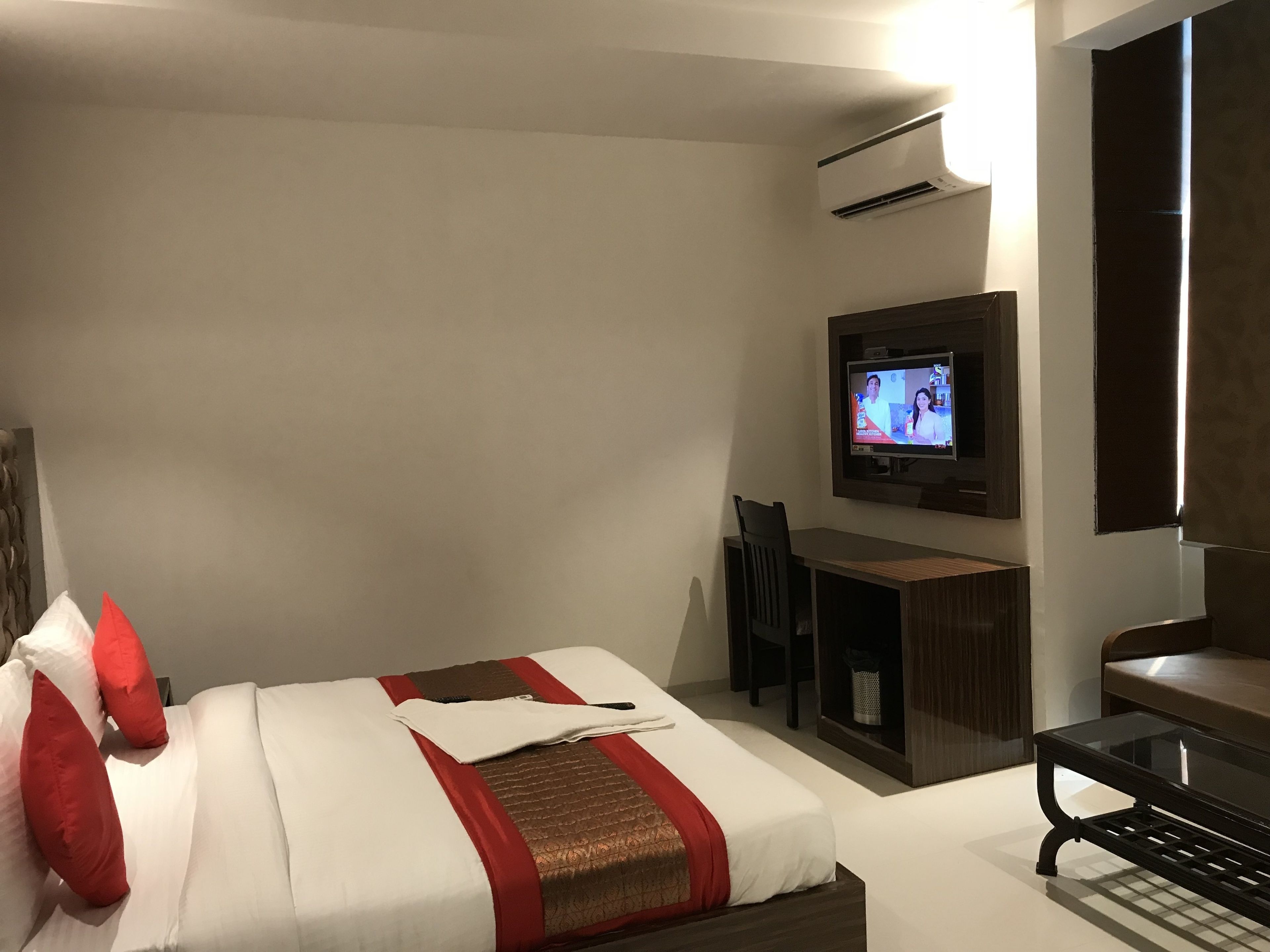 Une chambre d’hôtel équipée d’un lit, d’un téléviseur fixé au mur, d’un bureau et d’une chaise.