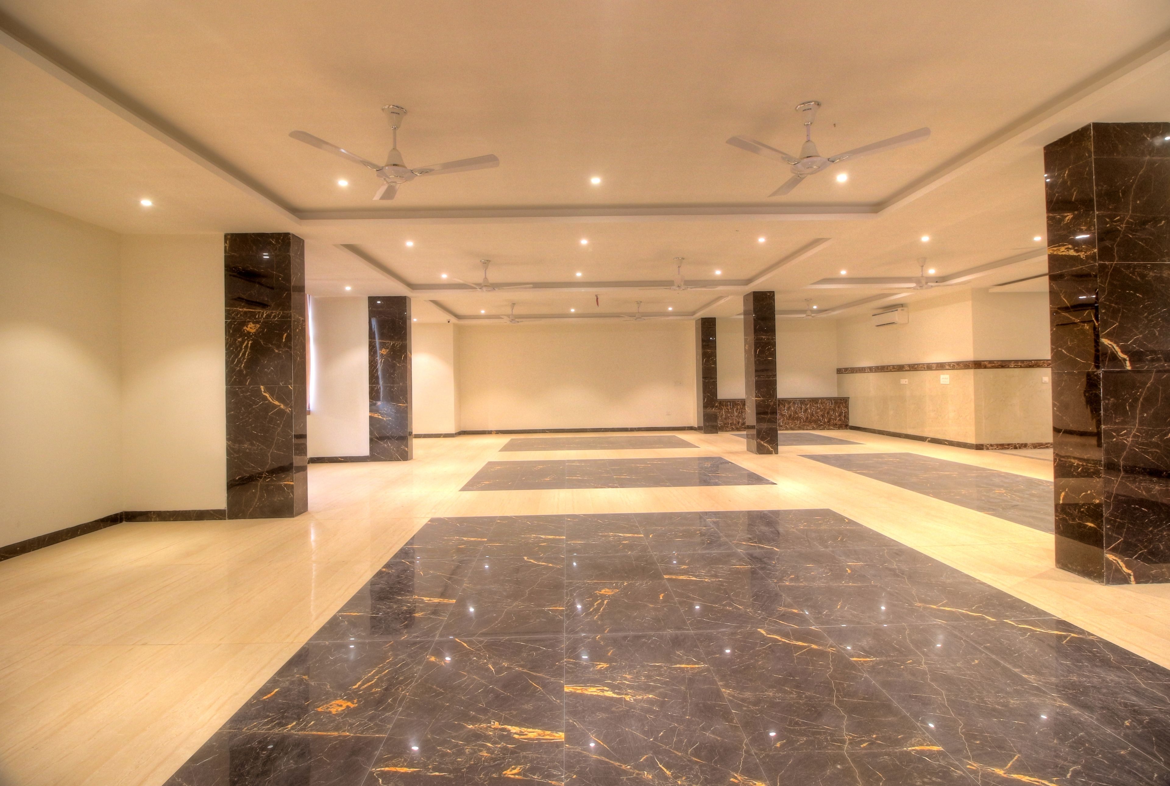 A spacious lobby with marble flooring, ceiling fans, and recessed lighting.