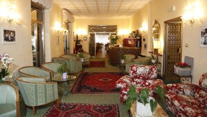 Un vestíbulo de hotel con un área de estar central, un bar y una recepción.