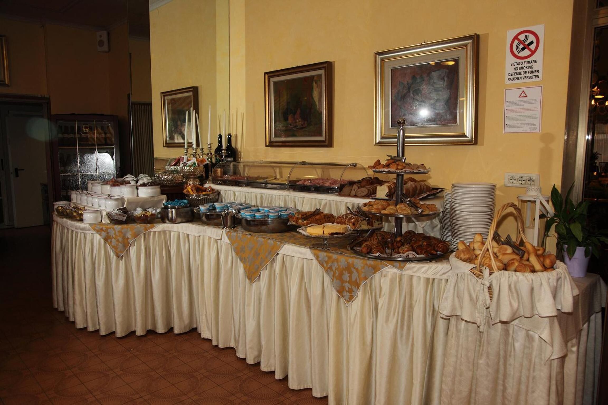 Una mesa de buffet con diferentes opciones de comida, un cartel de prohibido fumar y cuadros en la pared.