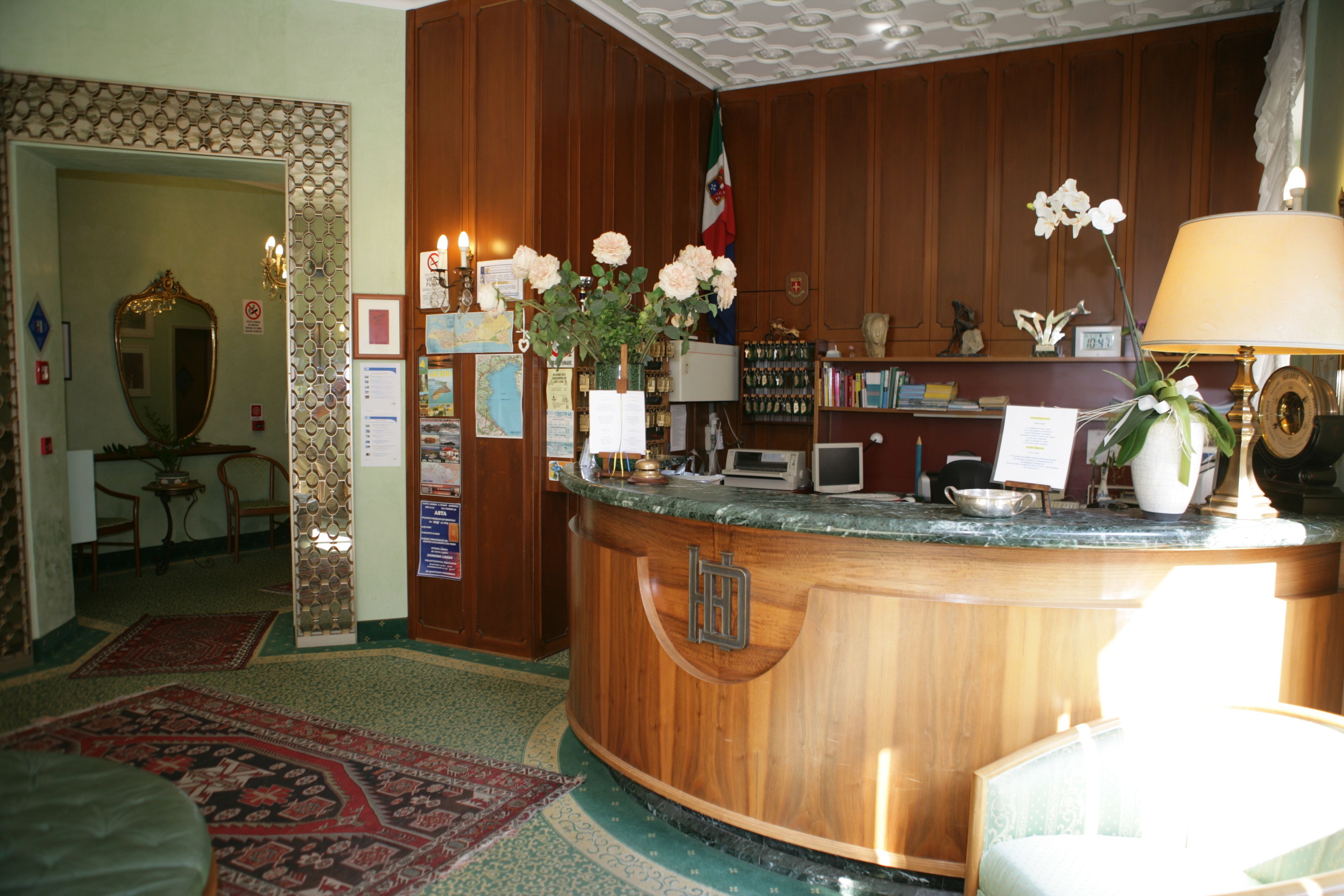 A reception area with a wooden counter, a flag, a map, and a flower vase.