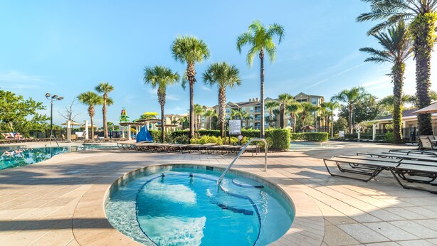 A swimming pool with a curved edge, surrounded by palm trees and lounge chairs. - Ly53790 - Windsor Palms Resort - 3 Bed 3 Baths Townhome (Kissimmee)