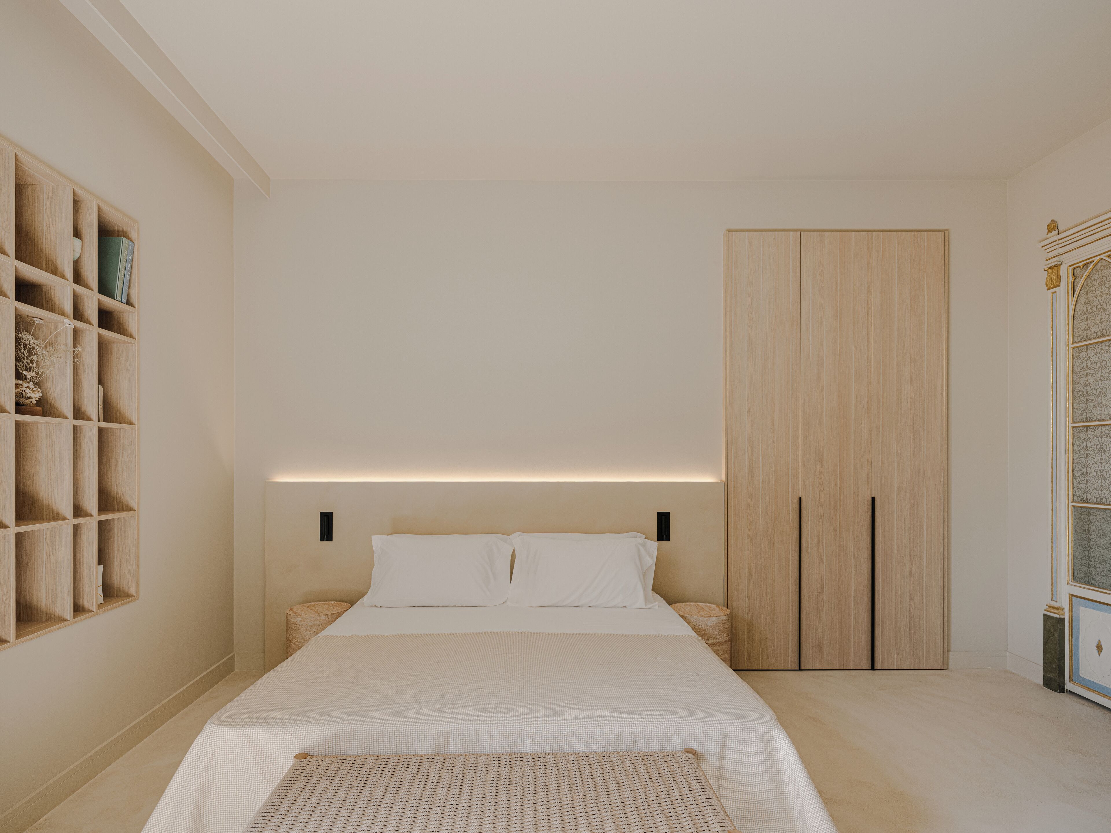 A bedroom with a bed, a wooden wardrobe, and a built-in bookshelf.