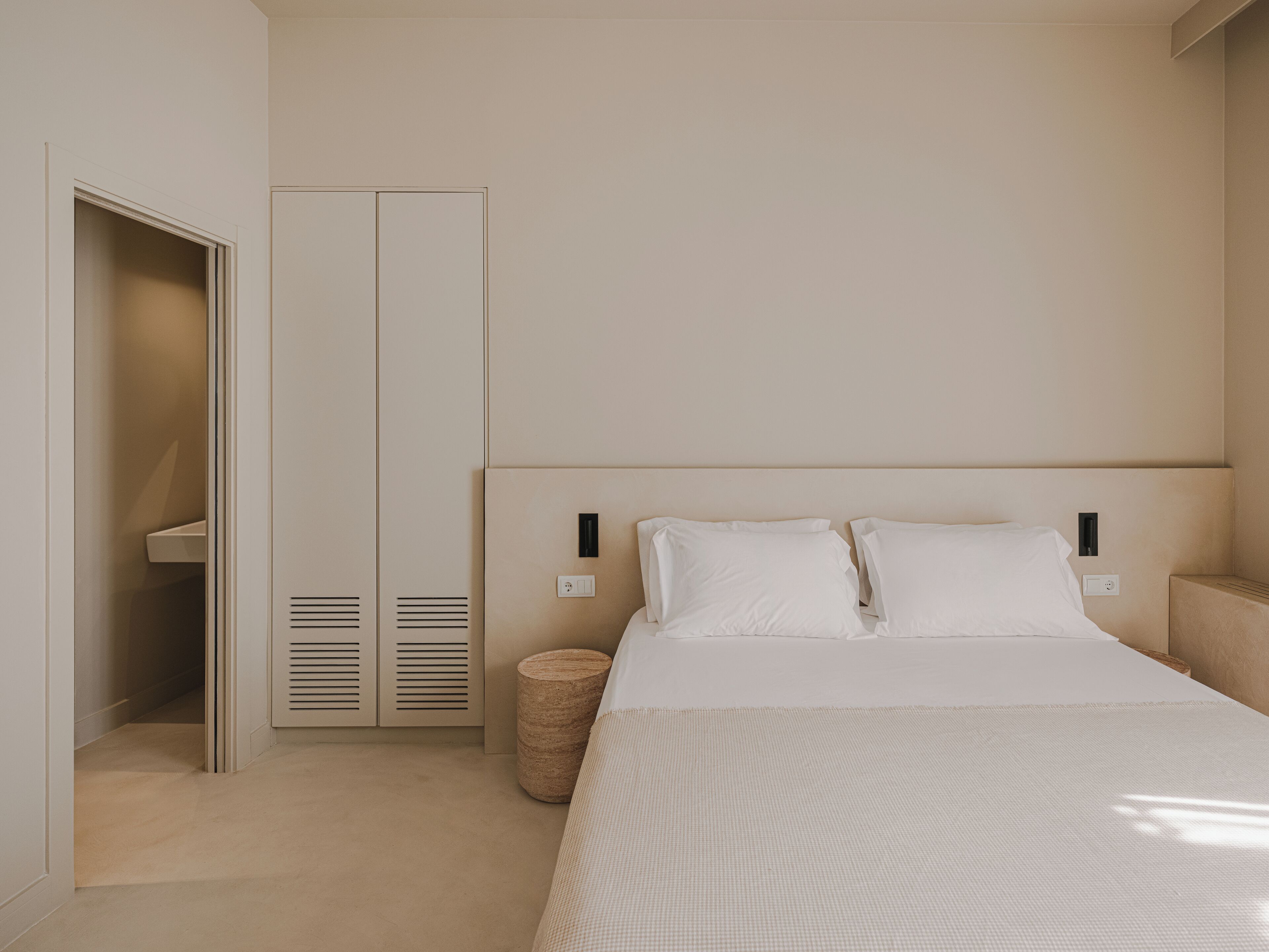 A bedroom with a bed, a wardrobe, and a bedside table.