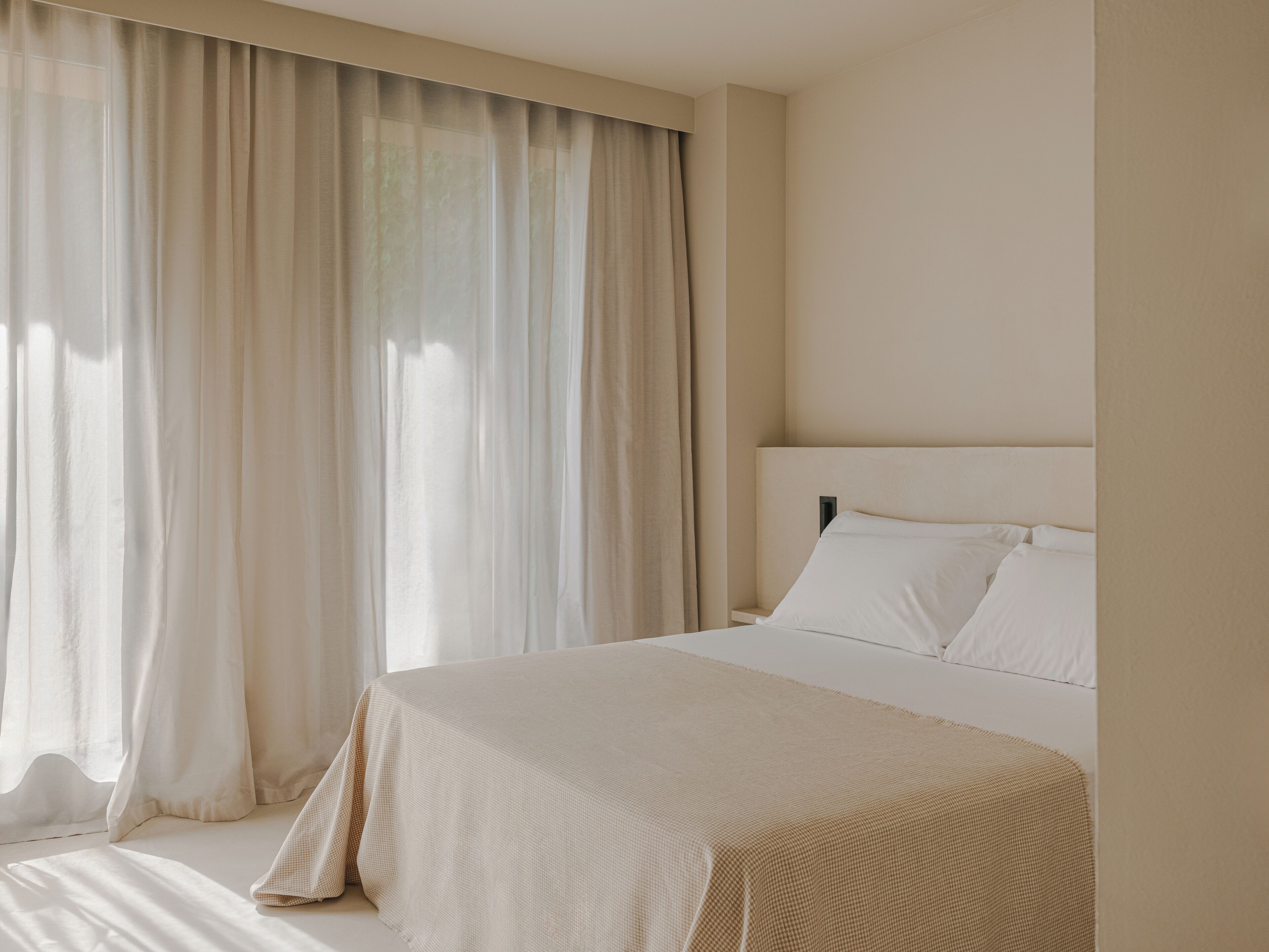 Un dormitorio con cama, cortinas y cabecera.
