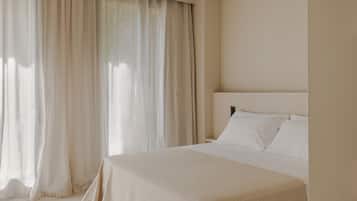 Un dormitorio con cama, cortinas y cabecera.