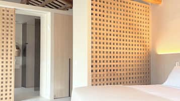 A bedroom with a bed, a wooden headboard, a wardrobe, and a door leading to a bathroom.