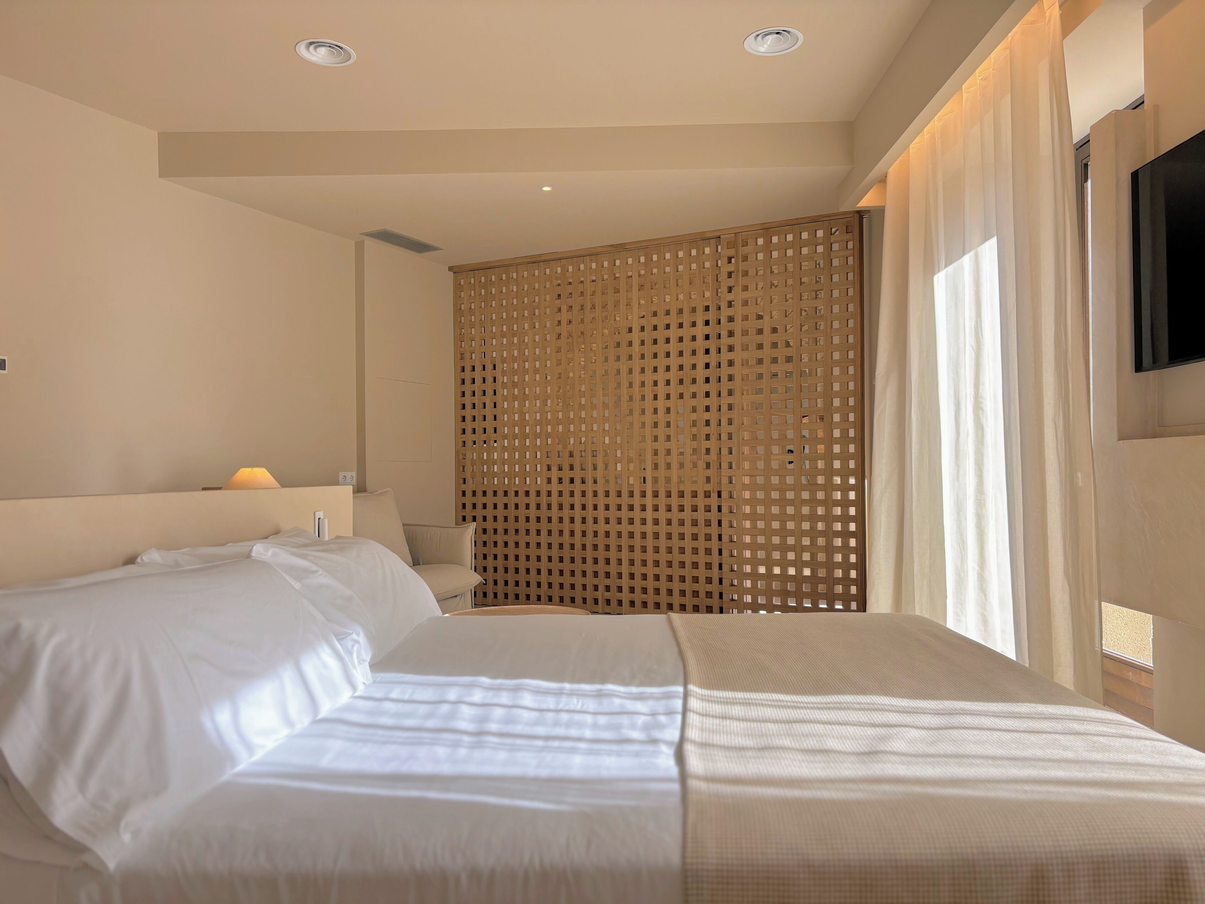Ein Hotelzimmer mit einem Bett, einer Holzwand, einer Lampe und einem an der Wand befestigten Fernseher.
