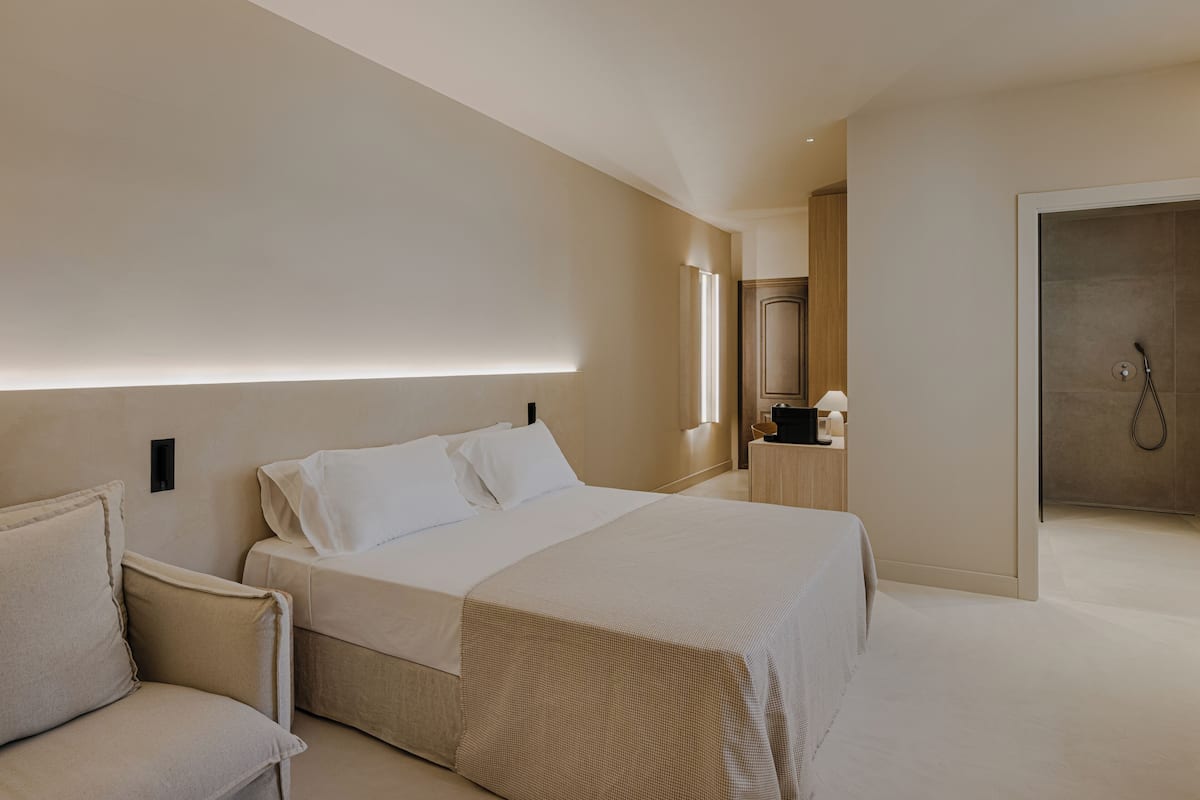 Une chambre d’hôtel moderne avec un grand lit, une table de chevet, une chaise et un espace douche.
