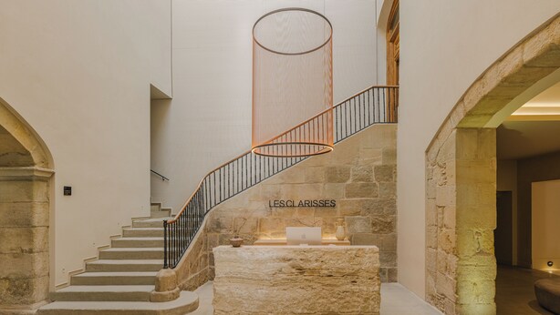 Un escalier en pierre avec une rampe métallique mène à un palier. Une plaque sur le palier indique : « LESCLARISSES ».